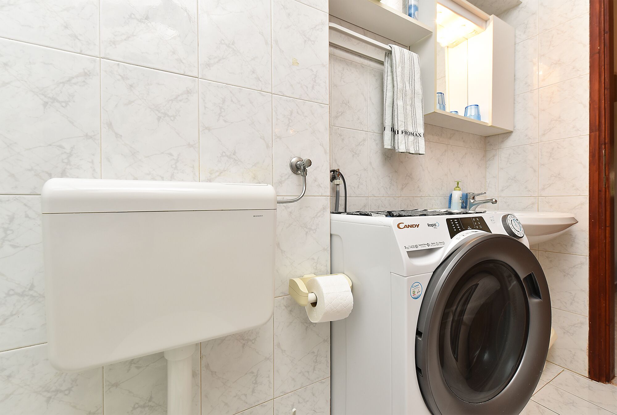 A modern bathroom with a toilet, washing machine, and sink.