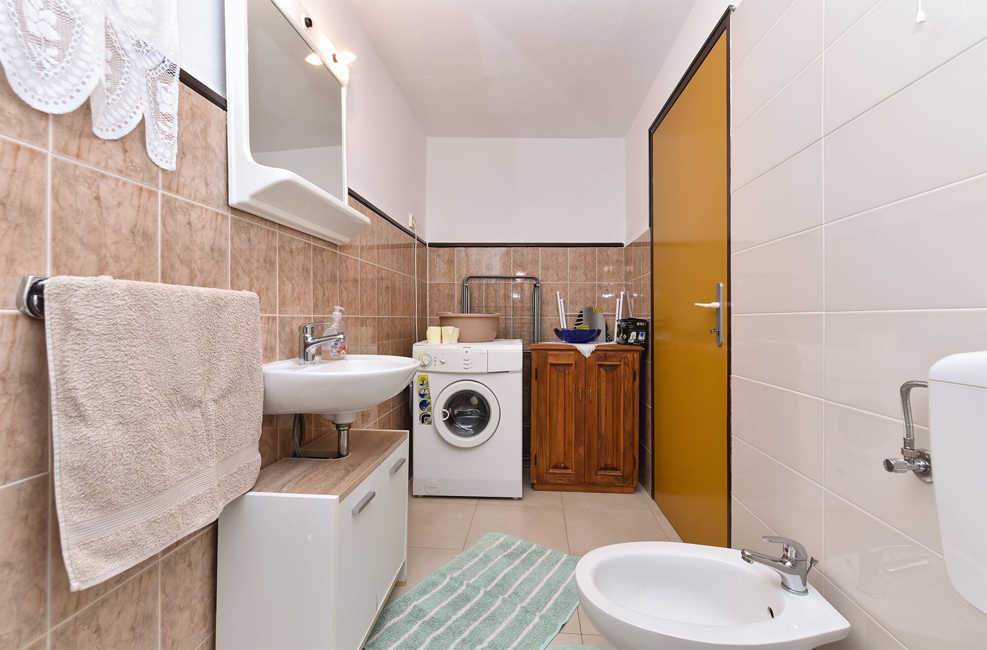 Un baño pequeño con lavamanos, espejo, lavadora y váter.