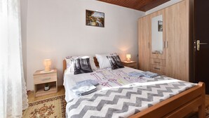 A bedroom with a wooden bed, a nightstand, a bedside lamp, a wardrobe, and a painting on the wall. - House 1009 (Svetvincenat)