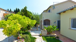 A courtyard with a stone pathway, potted plants, and a small fountain. - Apartment 1017 (Fazana)
