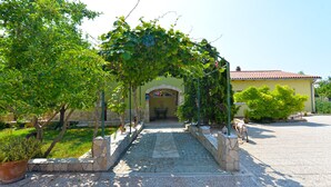A paved pathway leading to a building with a yellow facade and a red-tiled roof. - Apartment 1017 (Fazana)