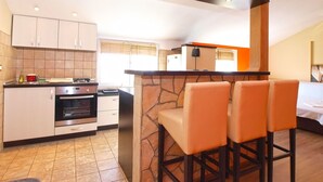 A modern kitchen with white cabinets, a built-in oven, and a stone island with bar stools. - Apartment 1017 (Fazana)