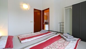 A hotel room with a bed, a wardrobe, and a kitchenette visible through an open door. - Apartment 1030 (Fazana)