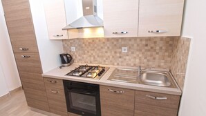 A modern kitchen with a gas stove, oven, and a coffee maker. - Apartment 1031 (Fazana)