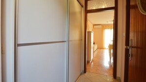 Un corridoio con una porta scorrevole che dà su una stanza con frigorifero e porta in legno.