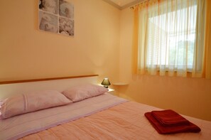 Un dormitorio con una cama, una mesita de noche, una lámpara, una ventana con cortinas y un adorno en la pared.