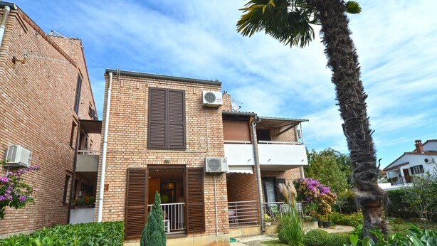 Un edificio in mattoni di due piani con un balcone e un condizionatore d'aria.