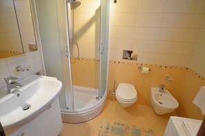 Un baño con ducha, inodoro, bidé y lavamanos.