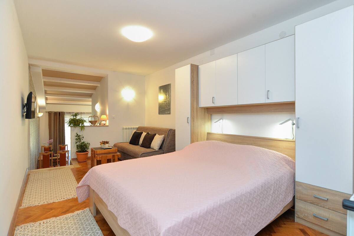 A bedroom with a large bed, a sofa, a small table, and a cabinet.