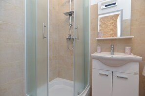 A modern bathroom with a glass-enclosed shower, a white sink, and a mirror above it.