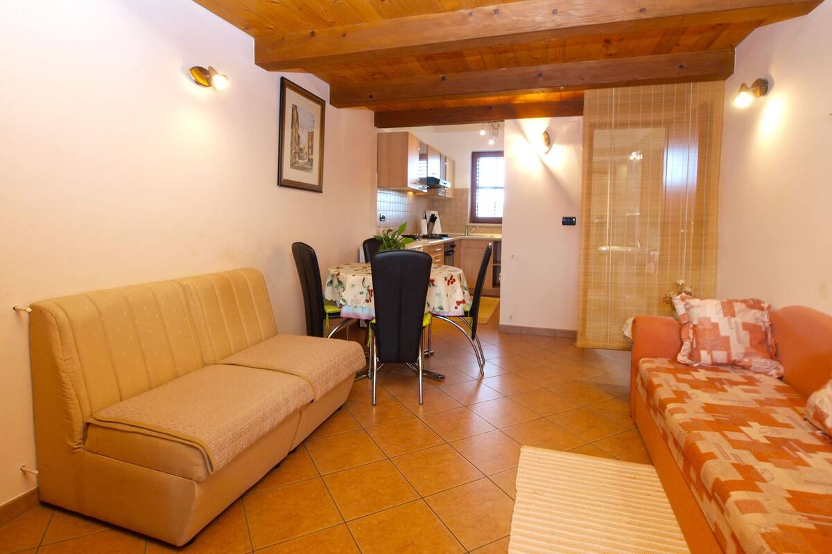 A living room with a beige sofa, a red sofa, and a dining area with a table and chairs.