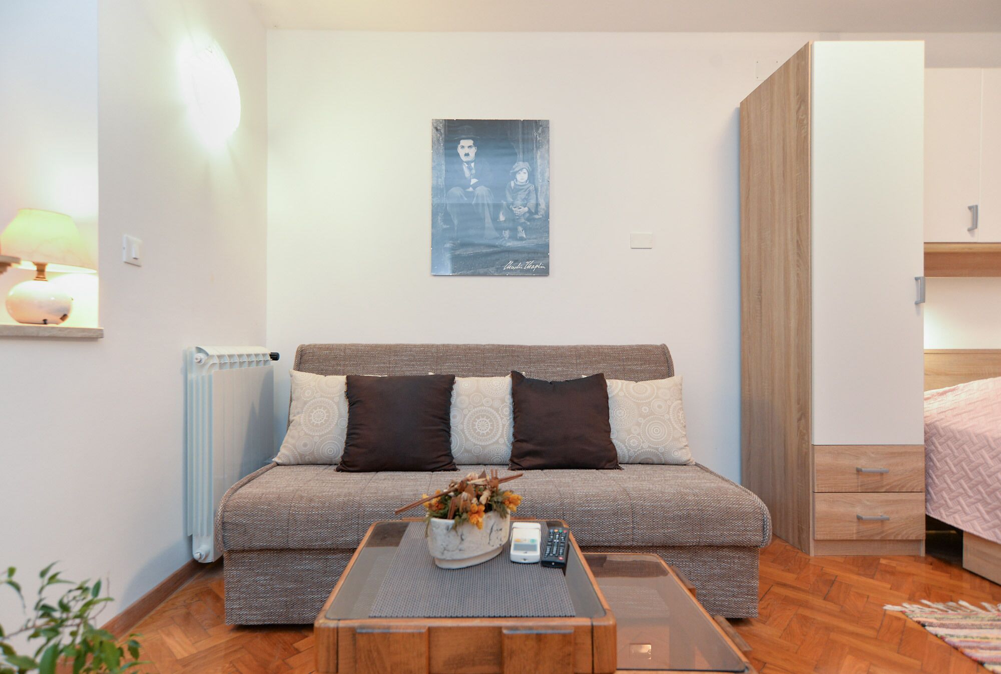 Una sala de estar moderna con un sofá, una mesa de centro con un jarrón, un control remoto y un radiador.