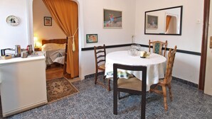 A room with a bed, a dining table with chairs, a chandelier, and a mirror on the wall. - Apartment 1050 (Rovinj)