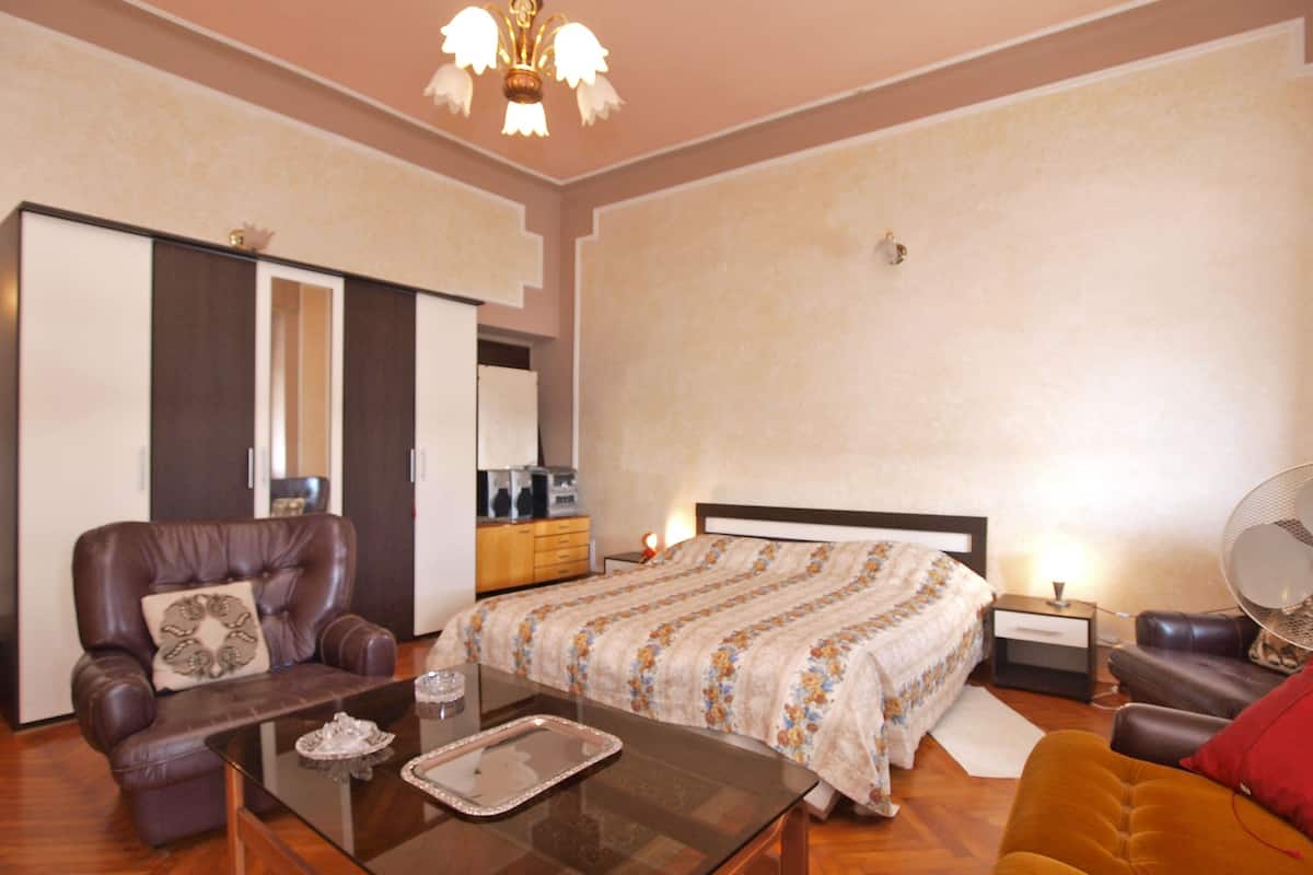A well-lit bedroom with a bed, a sofa, a coffee table, and a dresser.