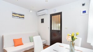 Ein moderner, hell eingerichteter Raum mit einem weißen Sofa, einem Esstisch und einem Blumenstrauß.