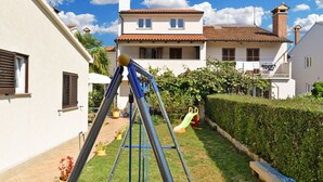Ein Wohngebiet mit einem weißen Haus, einer Schaukel und einer grünen Rutsche im Garten.