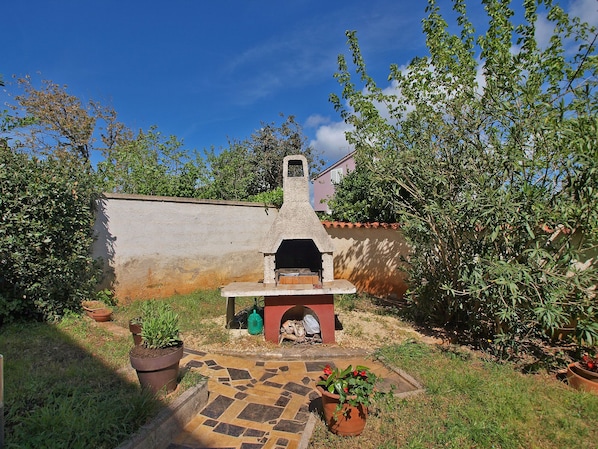 Enjoy al fresco dining with a traditional outdoor oven at the heart of this charming outdoor space.