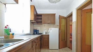 Une cuisine avec des meubles en bois, un réfrigérateur blanc et un sol carrelé.