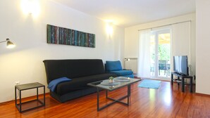 A living room with a black sofa, a coffee table, and a TV on a stand. - Apartment 1092 (Pula)