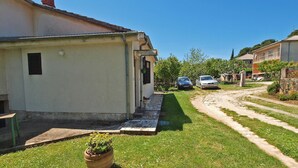 A residential area with a paved driveway, a lawn, and two parked cars. - Apartment 1095 (Pula)