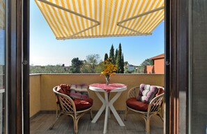 A balcony with wicker chairs, a small round table with a vase of flowers, and a striped canopy. - Apartment 1096 (Medulin)