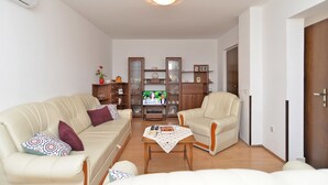 Un salon avec deux canapés beige, un meuble en bois et un téléviseur.