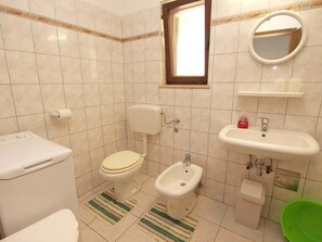 A bathroom with a toilet, bidet, sink, and a mirror.