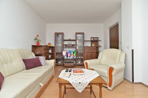 A living room with a beige sofa, a wooden coffee table, and a television. - Apartment 1098 (Fazana)