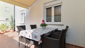 An outdoor patio with a table and chairs, a potted plant, and a window. - Apartment 1100 (Pula)