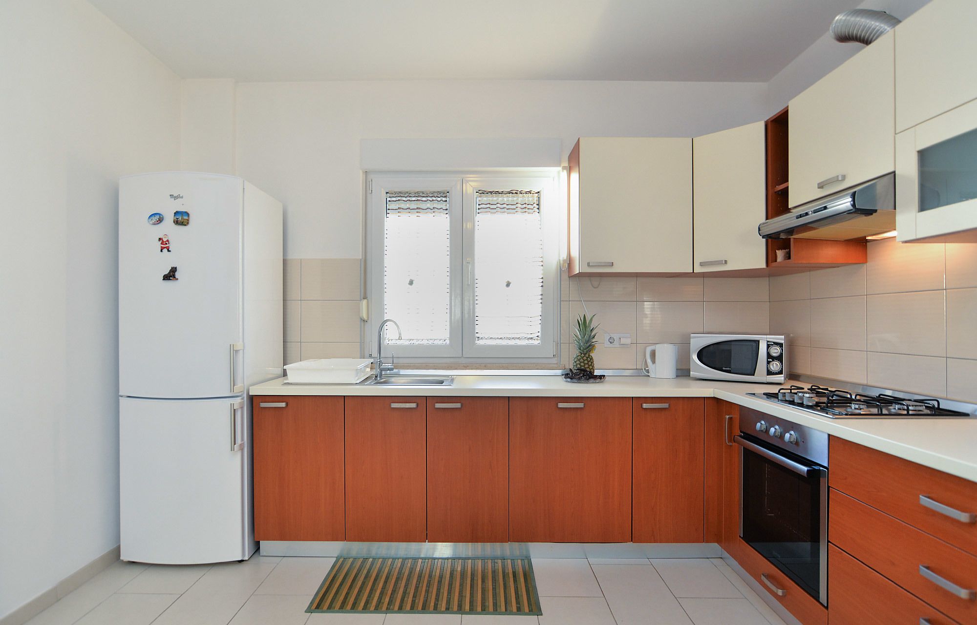 Eine moderne Küche mit Kühlschrank, Mikrowelle, Herd und Holzschränken.