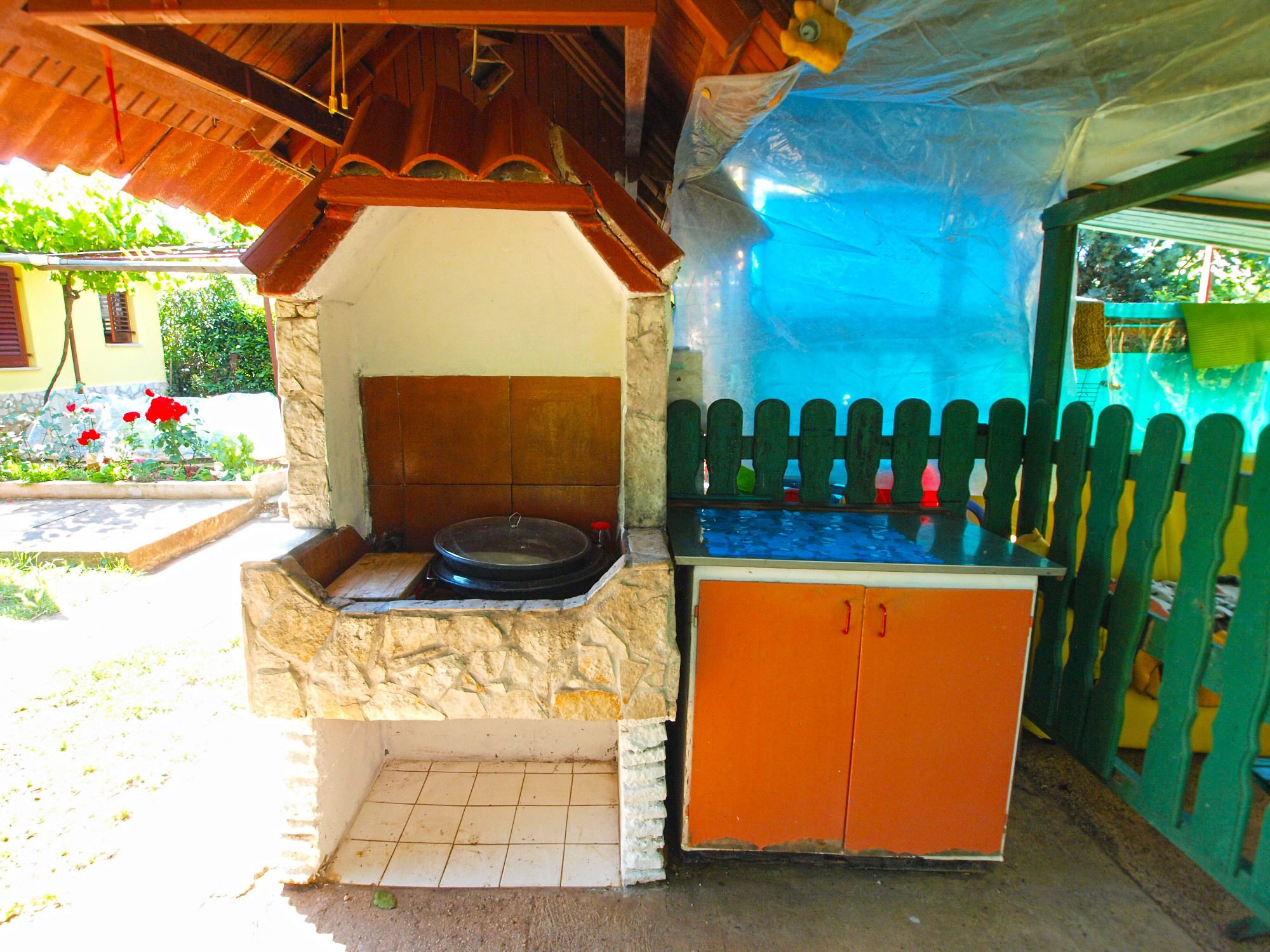 A stone-built outdoor kitchen with a tiled floor and a wooden counter.