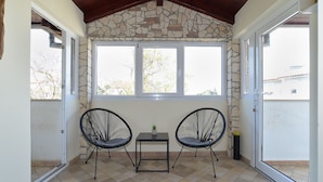 A balcony with two chairs, a small table, and a stone wall. - Apartment 1113 (Fazana)