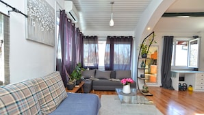 A modern living room with a sofa, a coffee table, and a dining area with a kitchen in the background. - Apartment 1113 (Fazana)