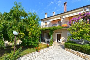 A two-story building with a balcony, stone pathway, and outdoor seating area.