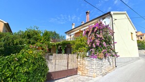 A two-story house with a stone wall and a wooden gate. - Apartment 1122 (Liznjan)