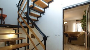 A staircase with wooden steps and black metal railings leading to a living area with a sofa and a plant. - Apartment 1123 (Vodnjan)