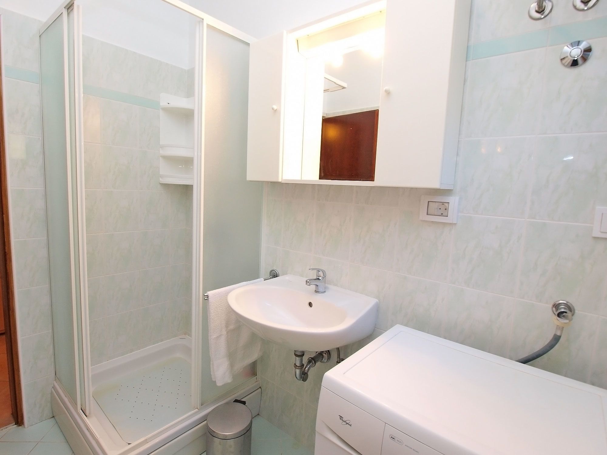 Un baño con ducha de vidrio, un lavabo blanco y un inodoro.