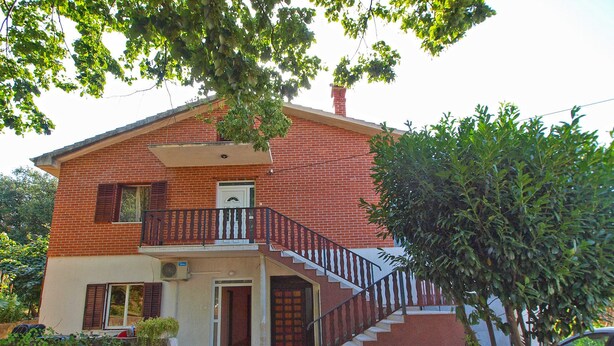 A two-story house with a brick exterior, a balcony with a railing, a front door, and a staircase leading to the upper floor. - Apartment 1157 (Pula)