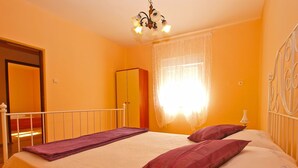 A bedroom with a bed, a wardrobe, and a window with curtains. - Apartment 1157 (Pula)