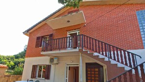 A two-story building with a balcony, a staircase, and a patio area with a table and chairs. - Apartment 1157 (Pula)