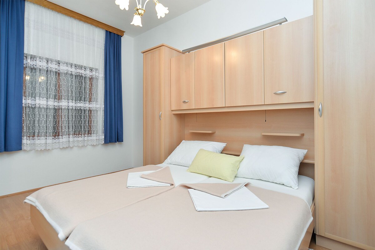 A bedroom with a bed, a wardrobe, and a window with curtains.