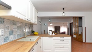 A modern kitchen with white cabinets, a wooden countertop, and a tiled backsplash. - Apartment 1168 (Fazana)