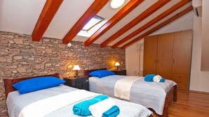 A room with two beds, stone walls, wooden beams, and a wardrobe. - Apartment 1175 (Pula)