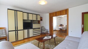 A living room with a sofa, a coffee table, and a TV. There is a dining area with a table and chairs. - Apartment 1198 (Medulin)
