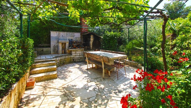 A garden with a stone bench, a small table, and a pergola structure. - Apartment 1198 (Medulin)