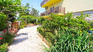 A garden pathway leading to a yellow building with a red balcony. - Apartment 1198 (Medulin)