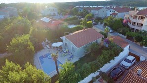 Un quartier résidentiel avec des maisons, une piscine et une voiture blanche garée dans la rue.