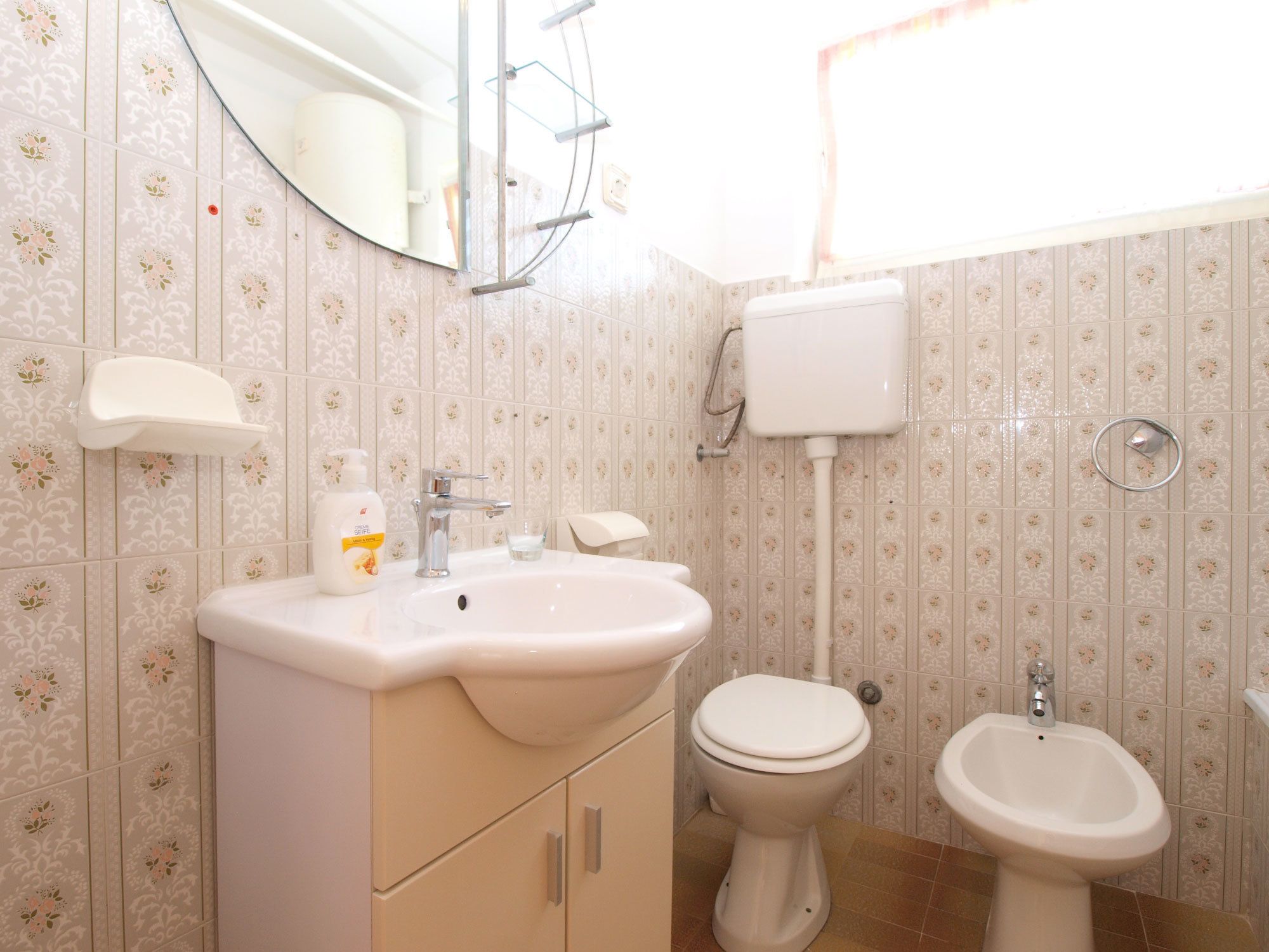 Et badeværelse med vask, toilet og bidet, alt sammen i hvidt.