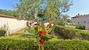 A garden with a clear sky, a white chair, and a house in the background. - Apartment 1203 (Pula)