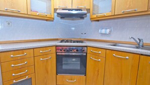 Una cocina con gabinetes de madera, horno empotrado, estufa a gas y un lavaplatos.